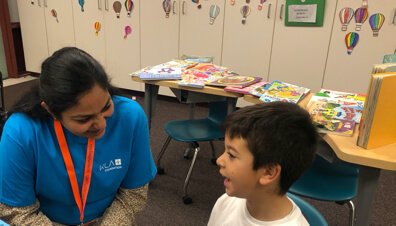 Employee talking to a young boy while volunteering for Reading Partners